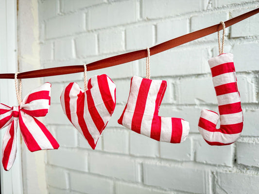 Finished handmade Christmas ornaments sewn in red and white striped fabric hanging as festive holiday decorations