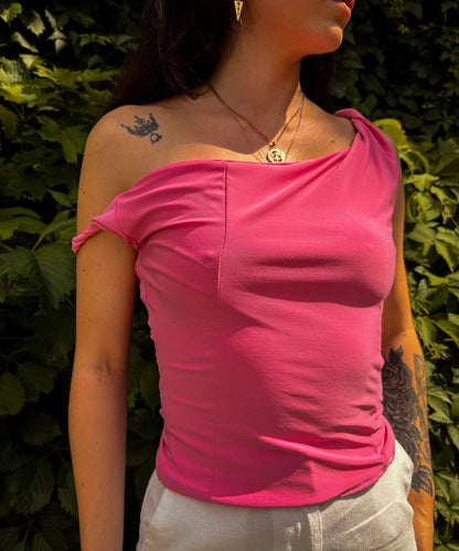 asmira asymmetric top sewing pattern with one shoulder design and twisted sleeve worn in pink fabric.