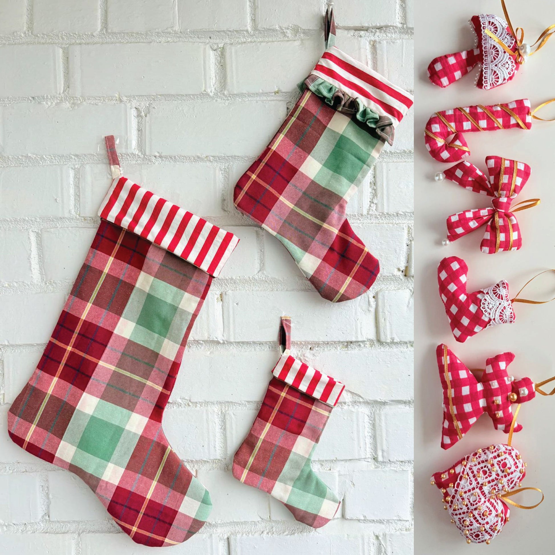 Three plaid Christmas stockings in red, green, and white hang on a white brick wall, with a vertical strip of matching fabric ornaments on the right including bows, candy canes, hearts, and stars.