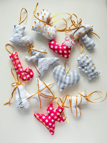 Handmade Christmas ornaments in heart and angel shapes sewn from patterned fabric with ribbon hangers on a light background.