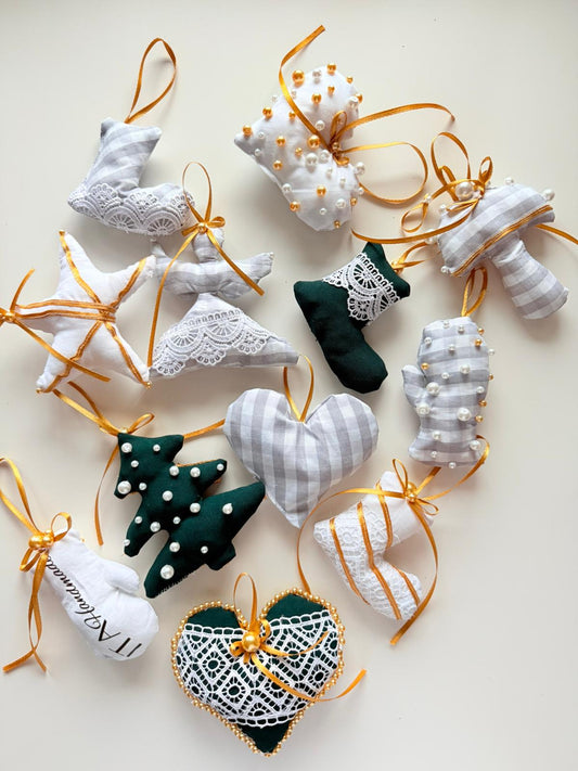 Collection of handmade Christmas ornaments in various shapes arranged on a light background, featuring fabric, lace, beads, and ribbon details from a sewing pattern set.