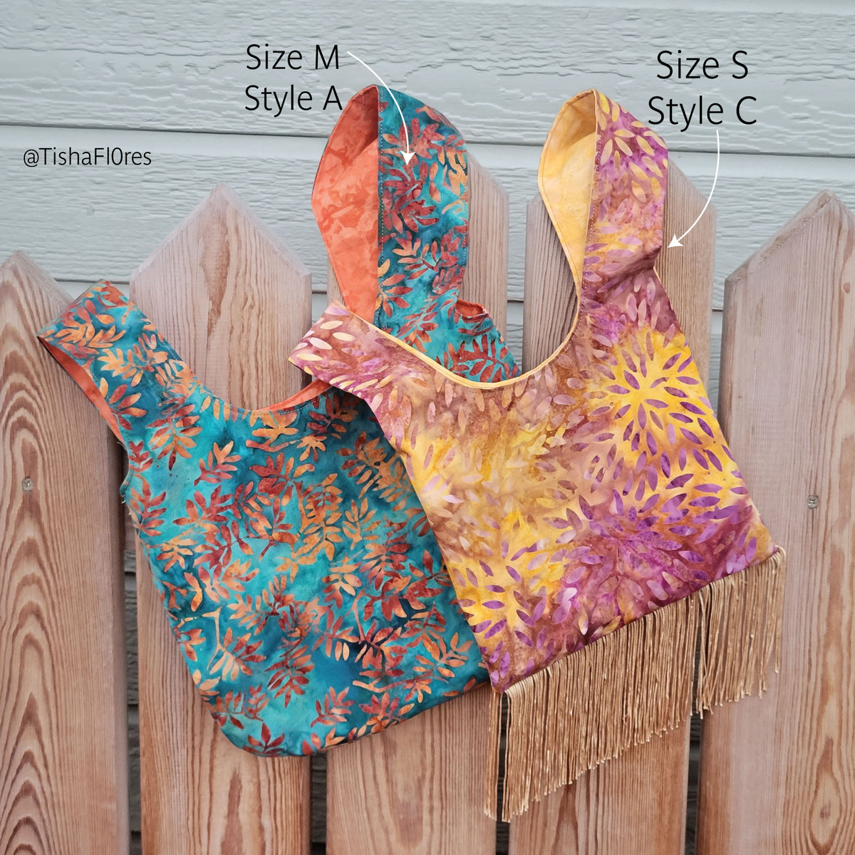 Two patterned fabric shopping bags made from a sewing pattern displayed on a wooden fence, labeled with arrows and text as Size M Style A and Size S Style C. One bag has a teal, orange, and gold leaf pattern, and the other has a yellow, orange, and purple floral pattern with fringe at the bottom.