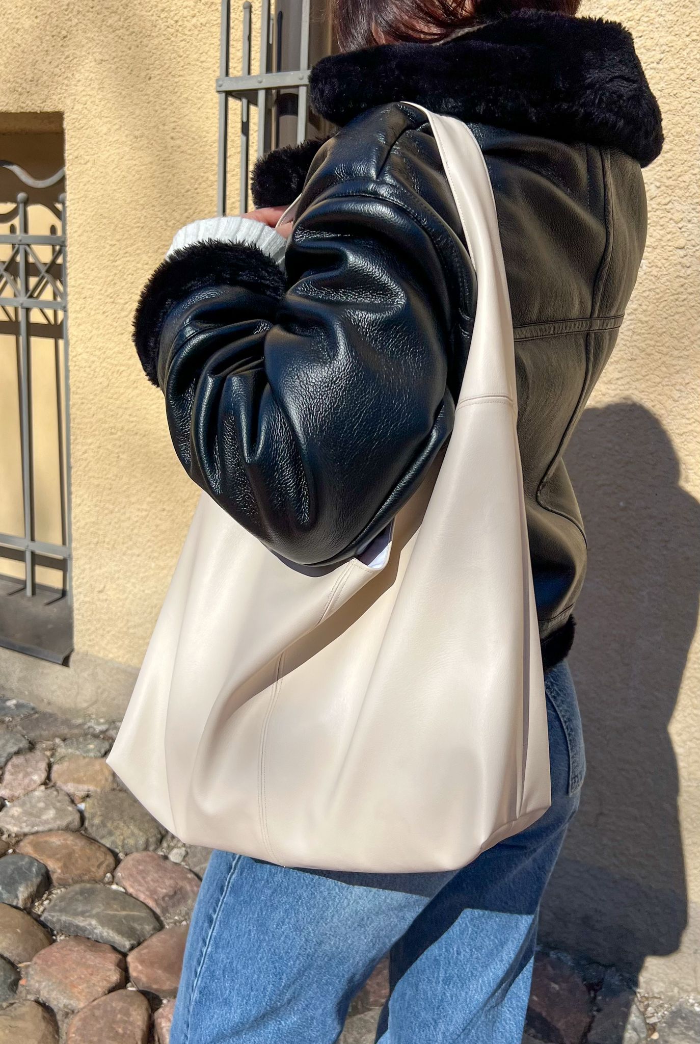 side view of the nova handbag worn on the shoulder showing soft slouchy leather shape and minimalist strap design from the sewing pattern.