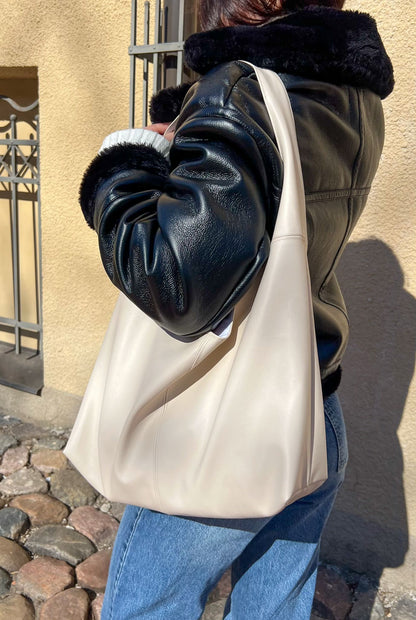 side view of the nova handbag worn on the shoulder showing soft slouchy leather shape and minimalist strap design from the sewing pattern.