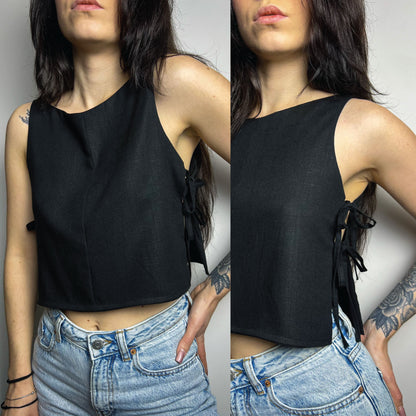A split view of a model wearing a black sleeveless crop top with side tie details, paired with light blue jeans, against a plain gray background.