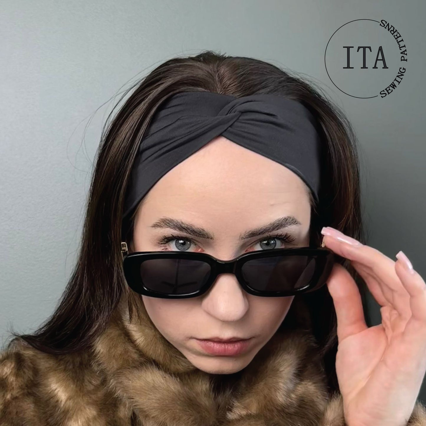 Woman wearing sunglasses and a black twisted style headband with 'ITA' sewing patterns logo in the corner.